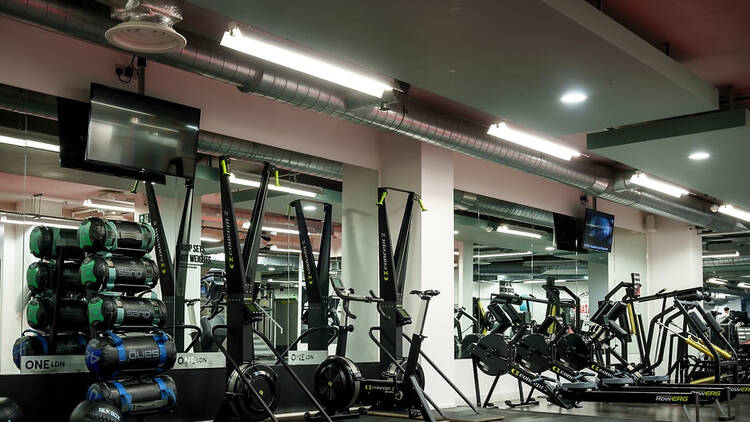 Interior of OneLDN Hyrox Gym showing ski trainers lined up against a wall
