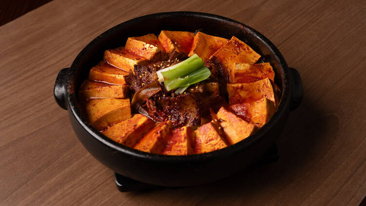 | A black cast iron pot with red gochujang and braised beef