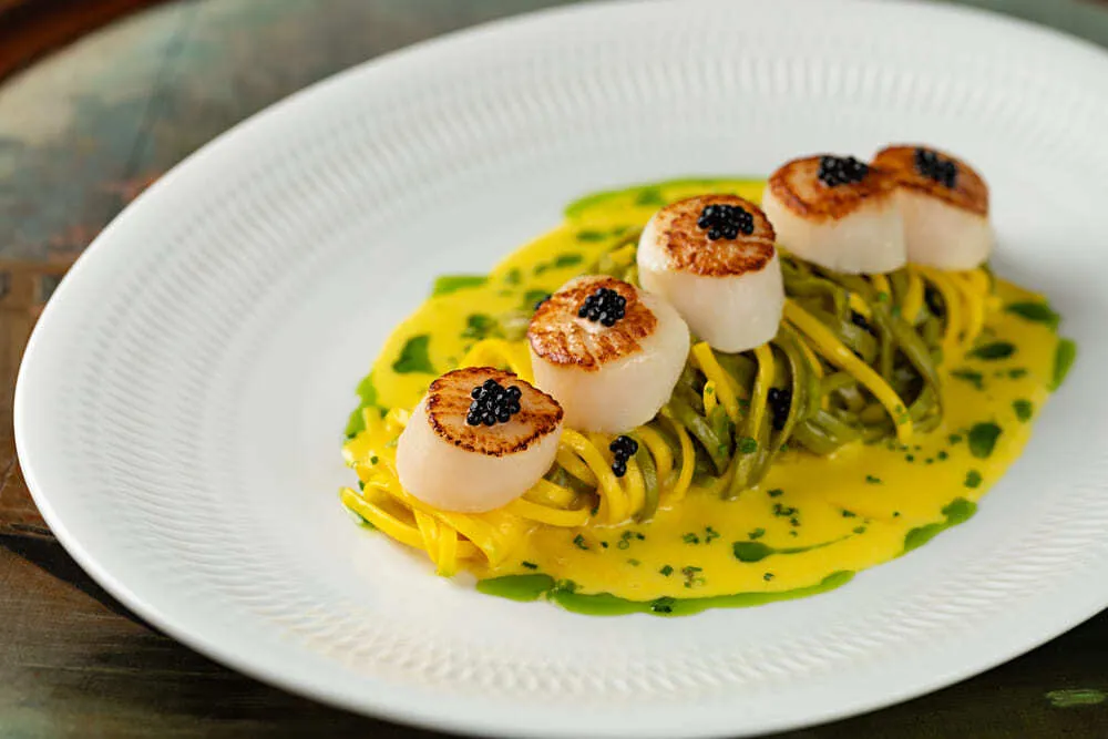 Vieiras canadenses seladas, paglia e fieno no molho de açafrão, limão siciliano, cebolete e caviar mujol do restaurante italiano Babbo Osteria