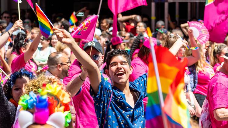 Man smiling looking at the camera amongst thousands of people wearing colorful costumes attending the World Pride March in NYC for LGBTQ+ rights. 