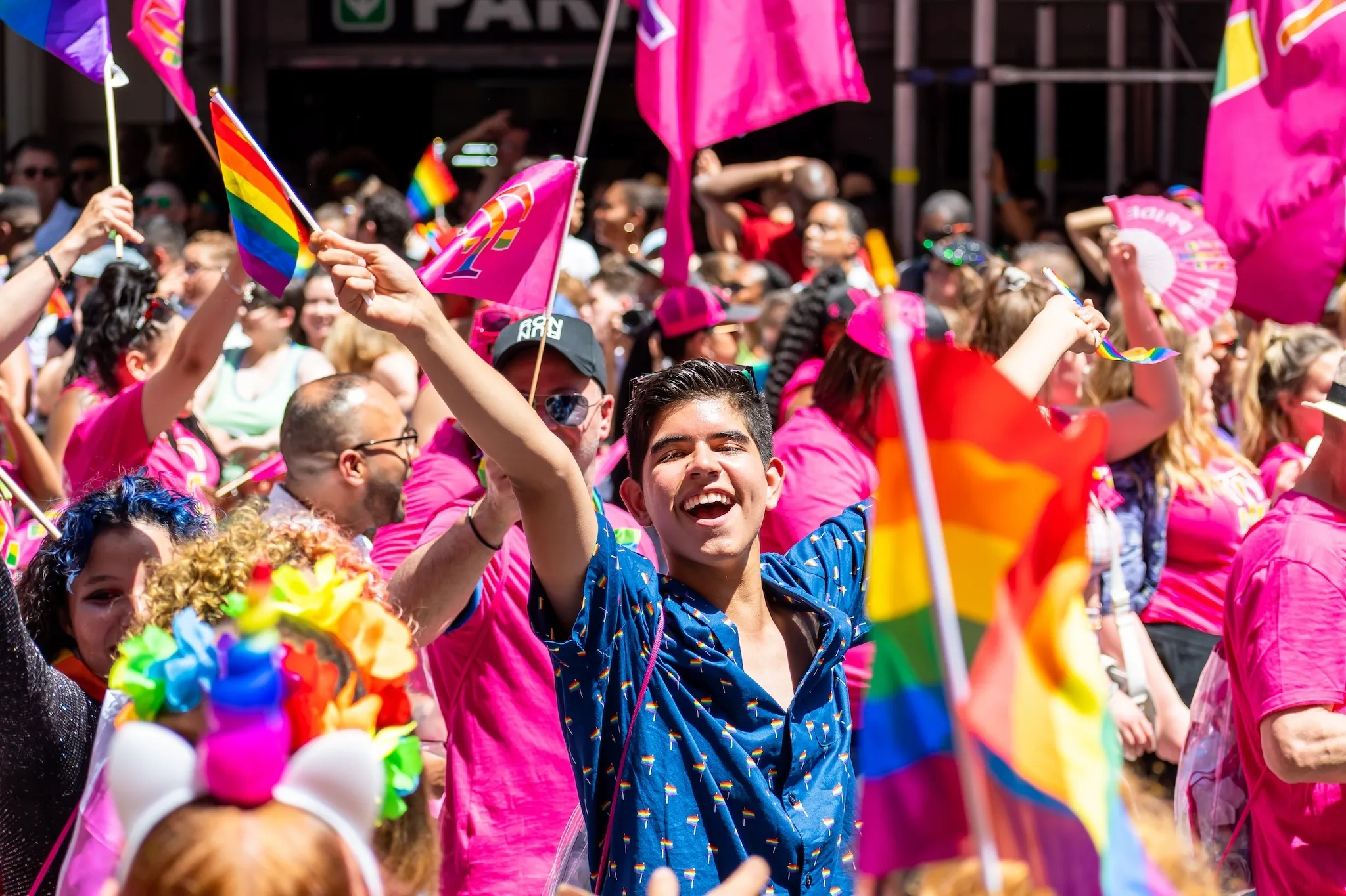 Man smiling looking at the camera amongst thousands of people wearing colorful costumes attending the World Pride March in NYC for LGBTQ+ rights.