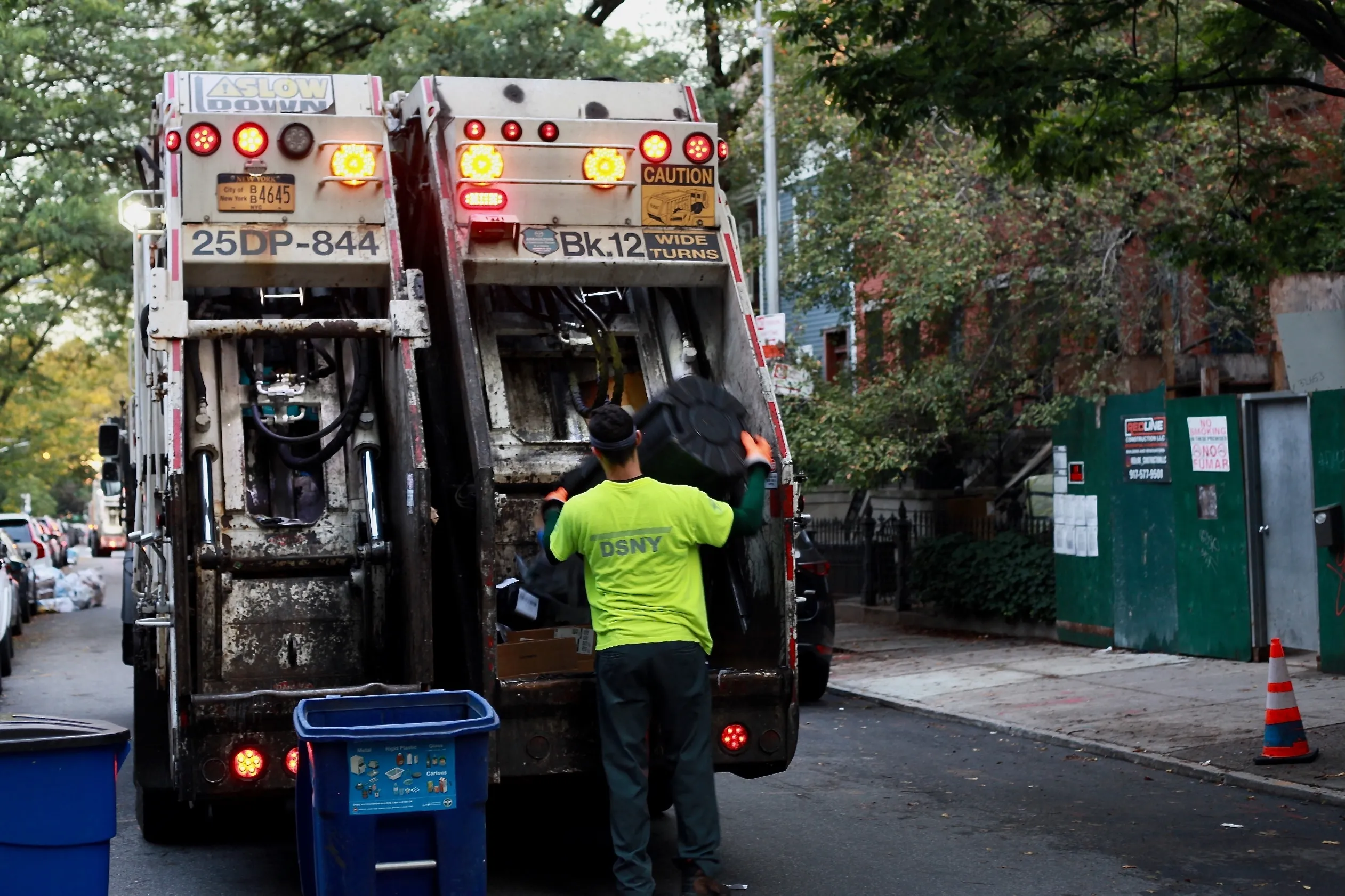 A garbage worker puts garbage into the back of a sanitation truck.