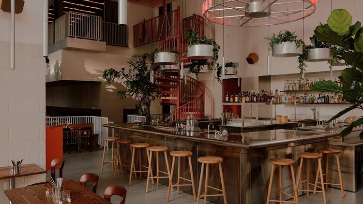 The bar with pink walls, bar stools and a neon light that says "papa san"