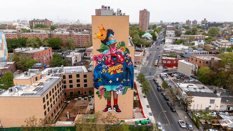 A large mural of a woman is seen on a building in Brooklyn.