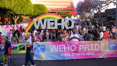WeHo Pride People hold signs for WeHo Pride along Santa Monica Boulevard.