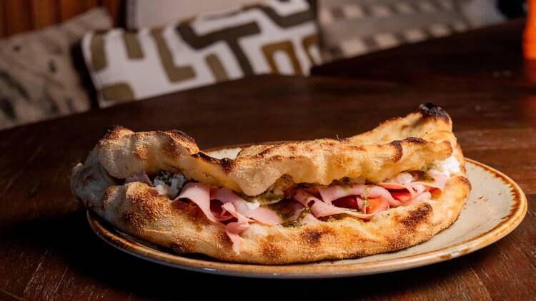 A Pizza Mortazza tem pesto de manjericão, mortadella, queijo burrata, tomate cherry e orégãos