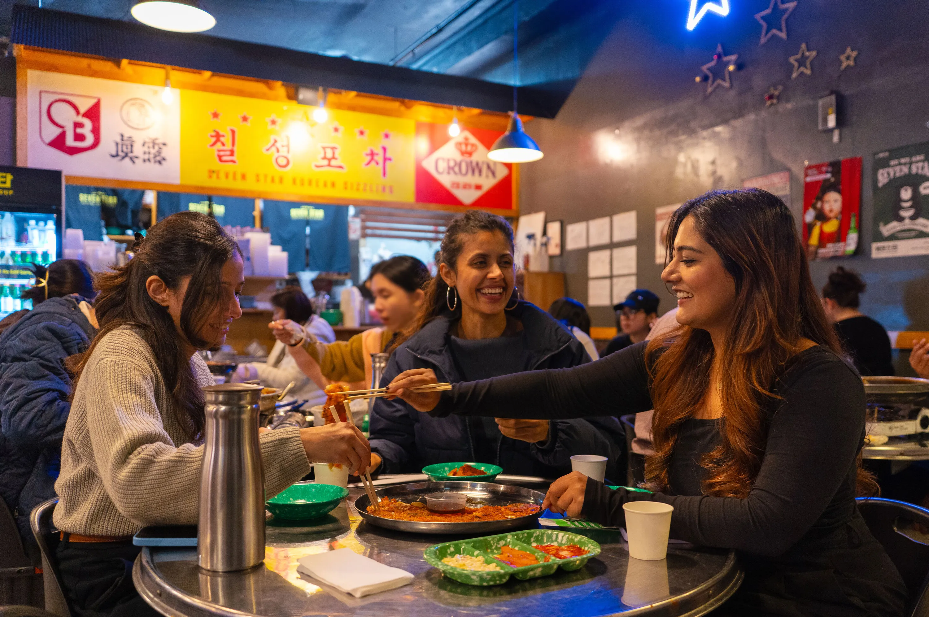 A trio of smiling women enjoying food at an eatery in Koreatown.