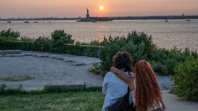 Two people hugging each other overlooking the Statue of Liberty