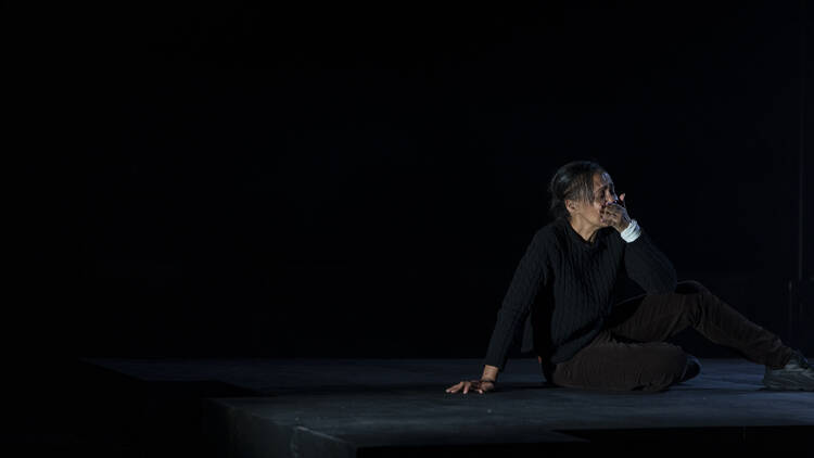 Paula Arundell sitting on the stage clasping her mouth in a scene from 'The Birds'.