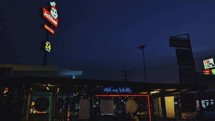 A sign that says Jollibee over a restaurant at night