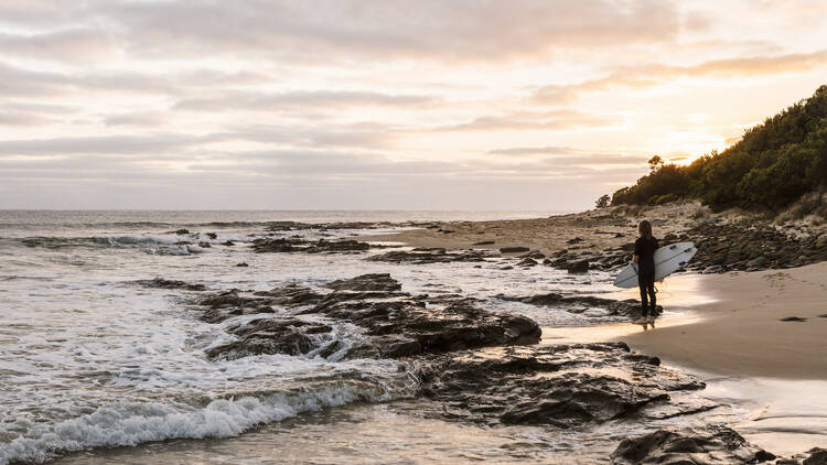 A surfer walking along the beach at Kennett River.