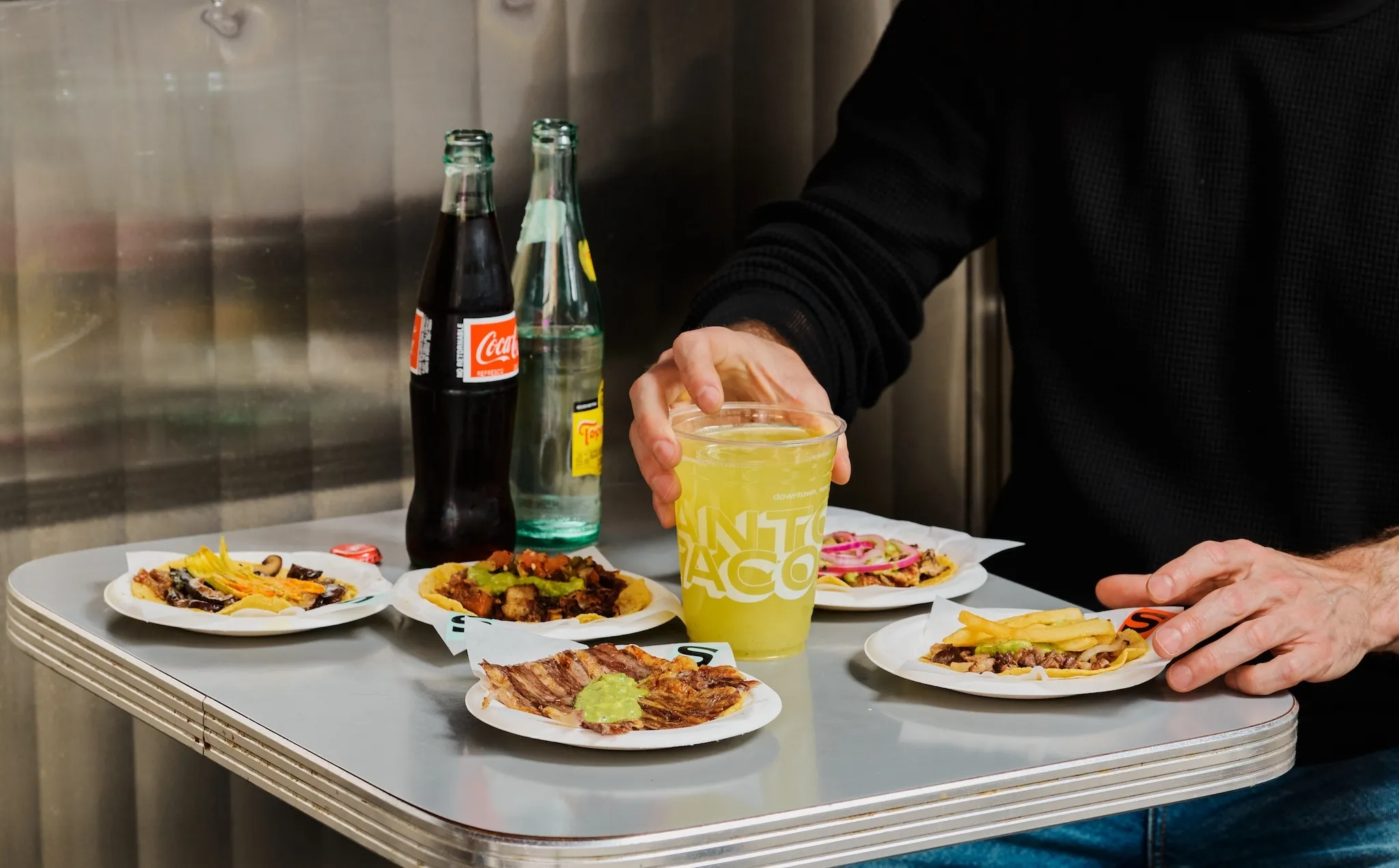 A table with tacos and a yellow drink that says "Santo Taco"