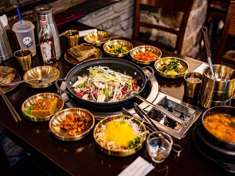 A vibrant display of traditional Korean dishes. Various colorful plates of bibimbap, kimchi, bulgogi, and other local delicacies are arranged attractively