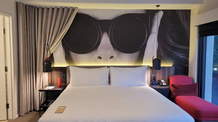 A bed with a photo of a woman in sunglasses above it