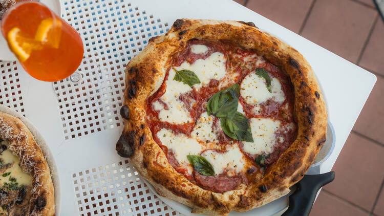 Margherita pizza on white table with cocktail