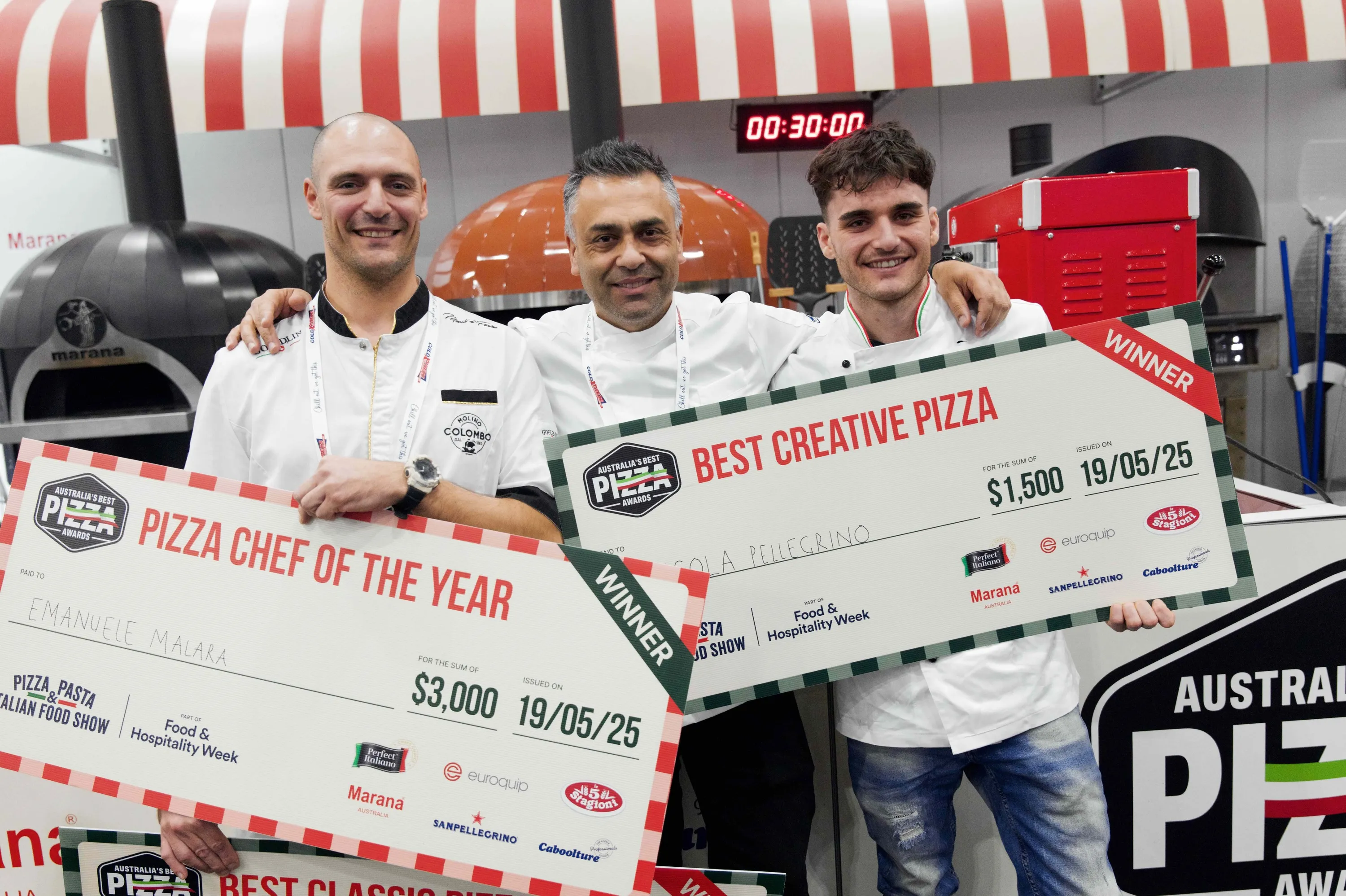 Three chefs holding big award posters