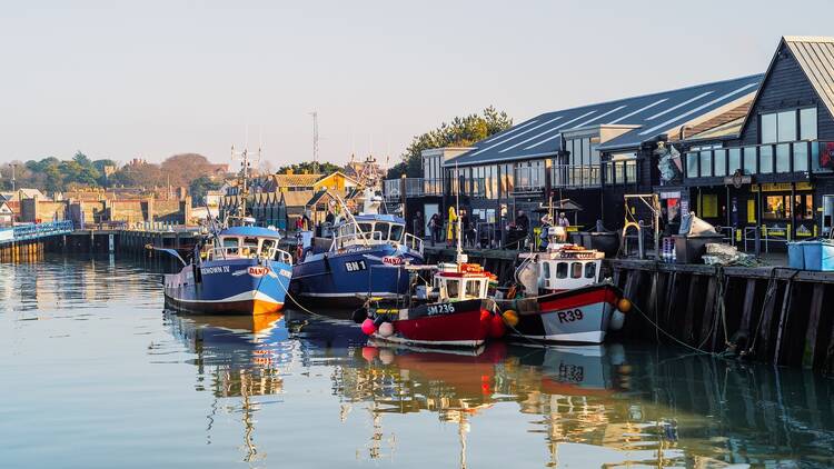 Colourful fishing boats in Whitstable harbour on a bright winter day.