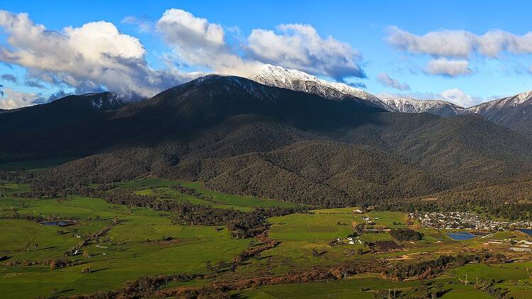 A mountain range with a blue sky above and green valley below. 