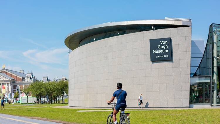 An Asian solo traveler from the bicycle cycling city sightseeing in front of Van Gogh museum in downtown Amsterdam.