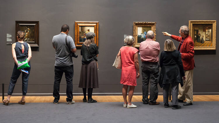  A museum guide and tourists look at the artwork of Johannes Vermeer, inside the Rijksmuseum