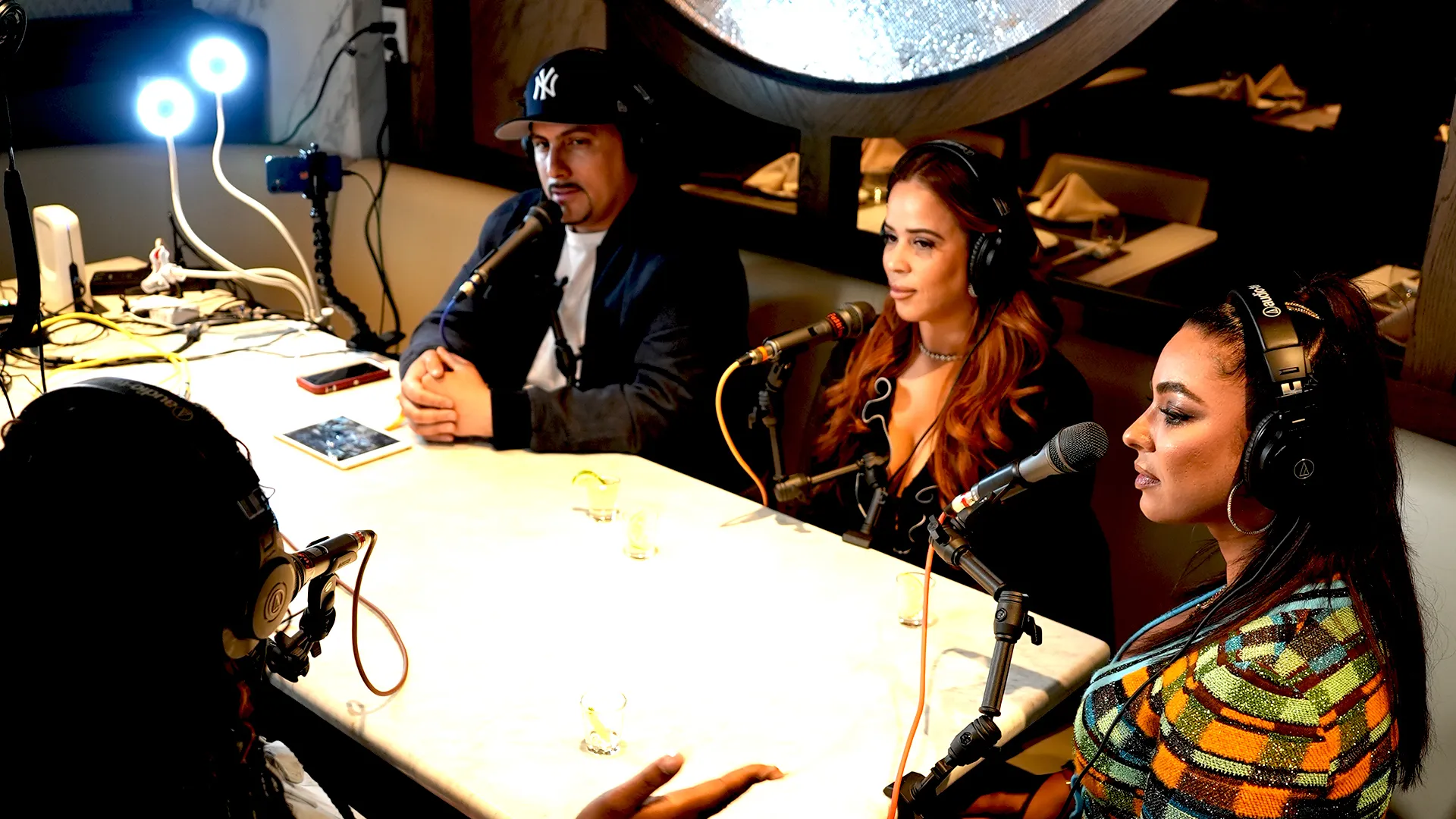 A group of people sitting around a table with podcast equipment