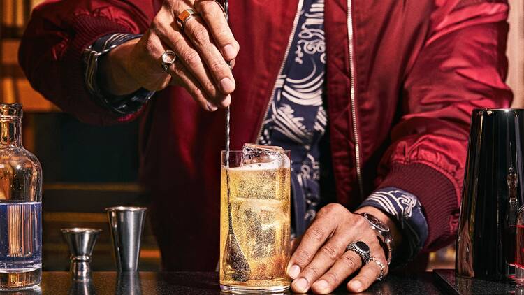 A person with a red shirt stirring a highball
