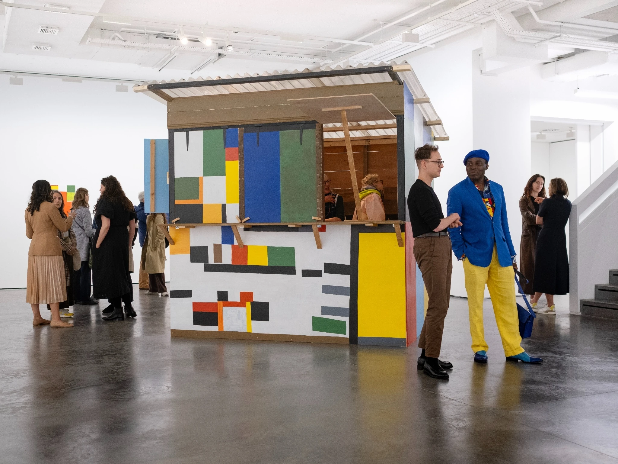 Ten people stand around looking at an exhibition at Goodman Gallery during London Gallery Weekend 2024