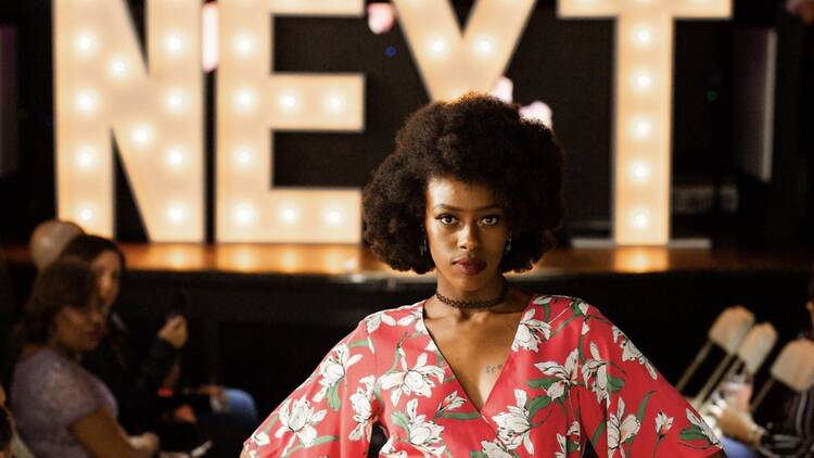 model on stage in front of sign that says NEXT model on stage in front of sign that says NEXT