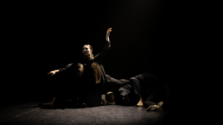 three dancers on stage dressed in black