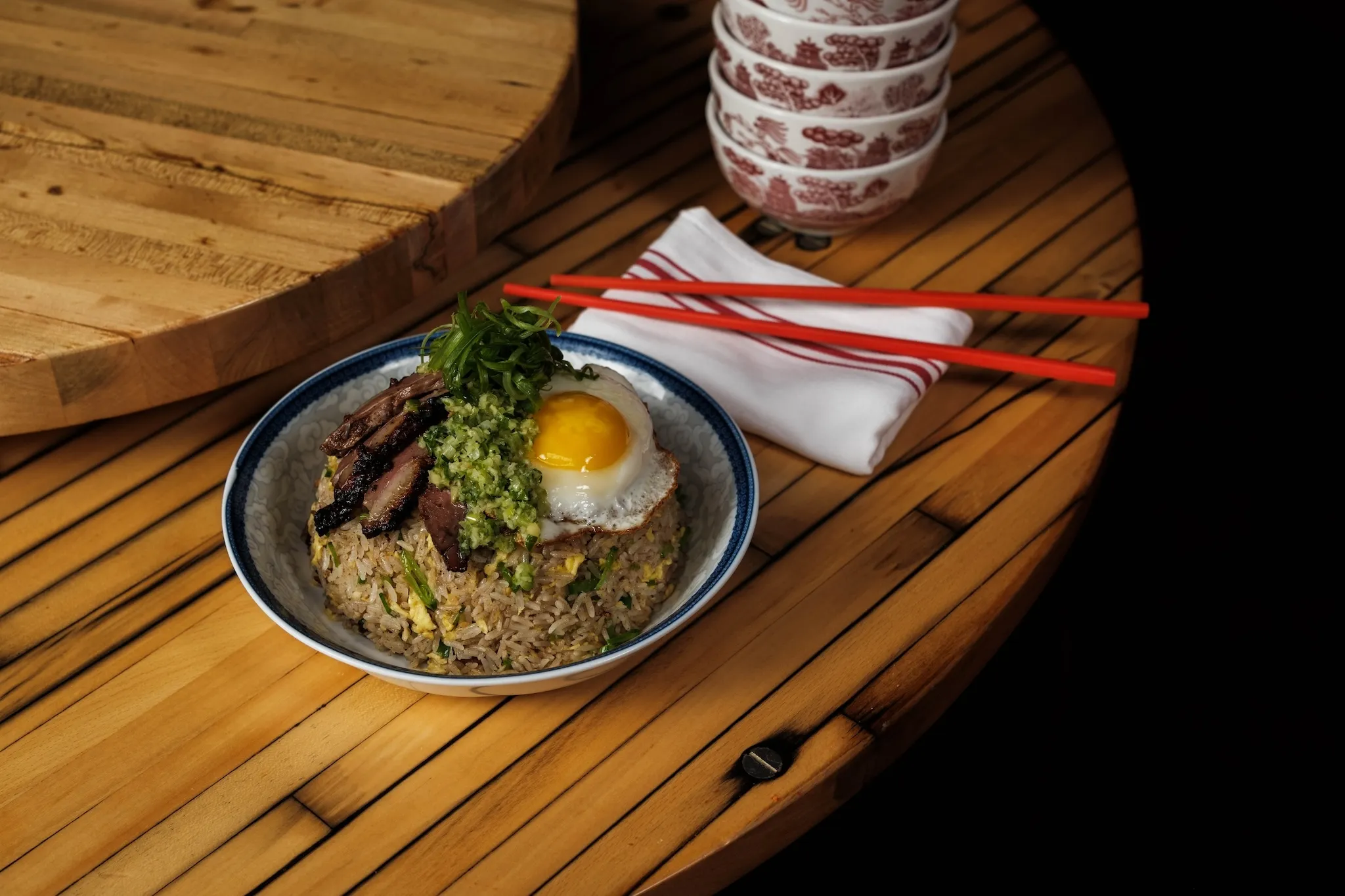 A bowl of duck fried rice with red chopsticks