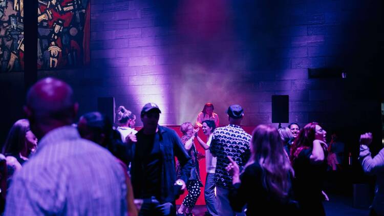 People dancing in front of a DJ booth. 
