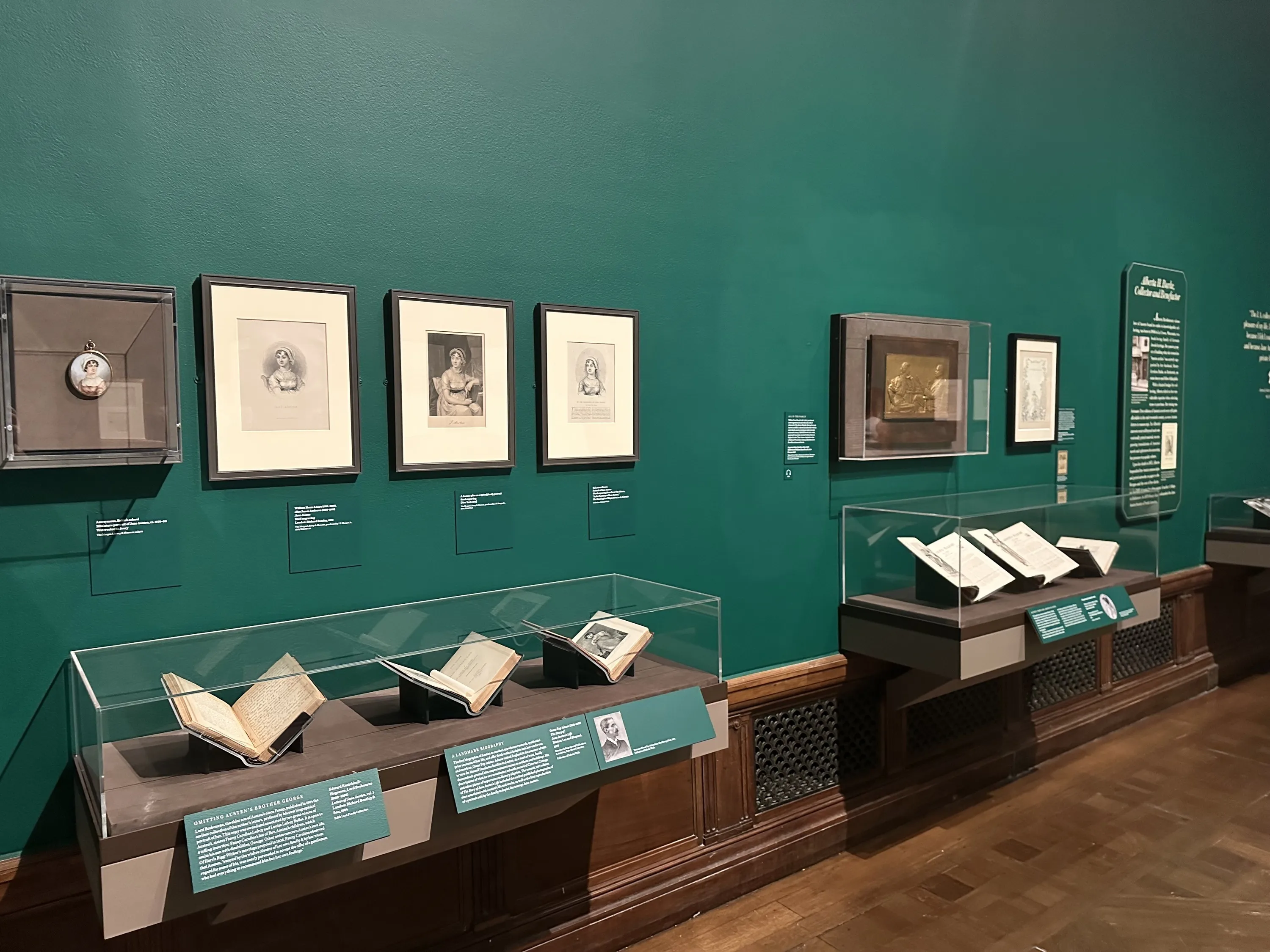 An exhibit about Jane Austen with green walls and books on display.
