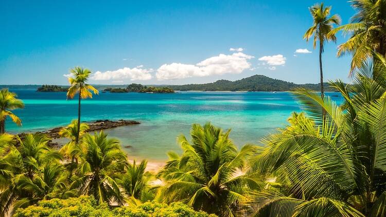 Blue sea, palm trees and distant hills in Coiba, Panama