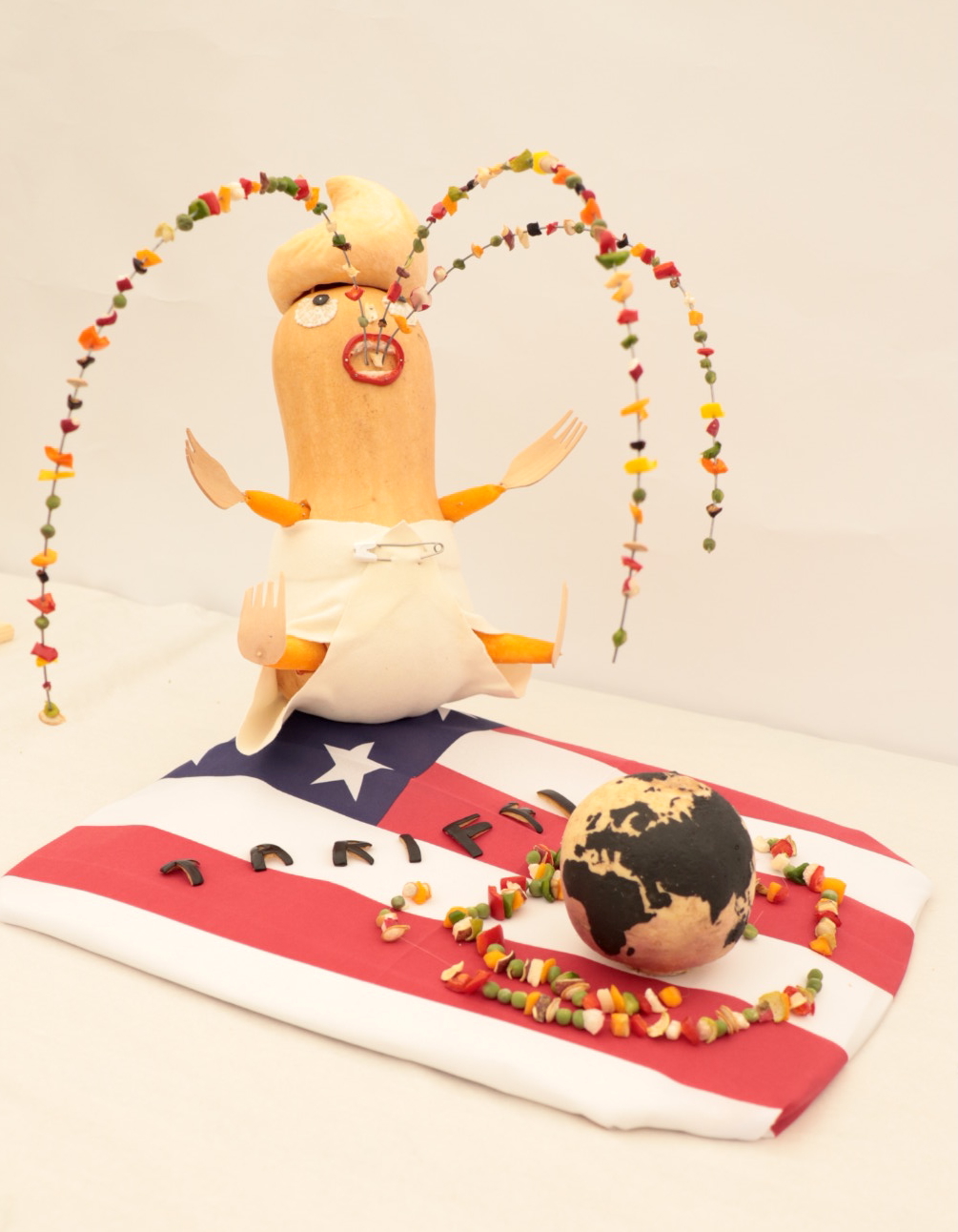 Vegetable sculpture of Donald Trump puking over the world on an American flag