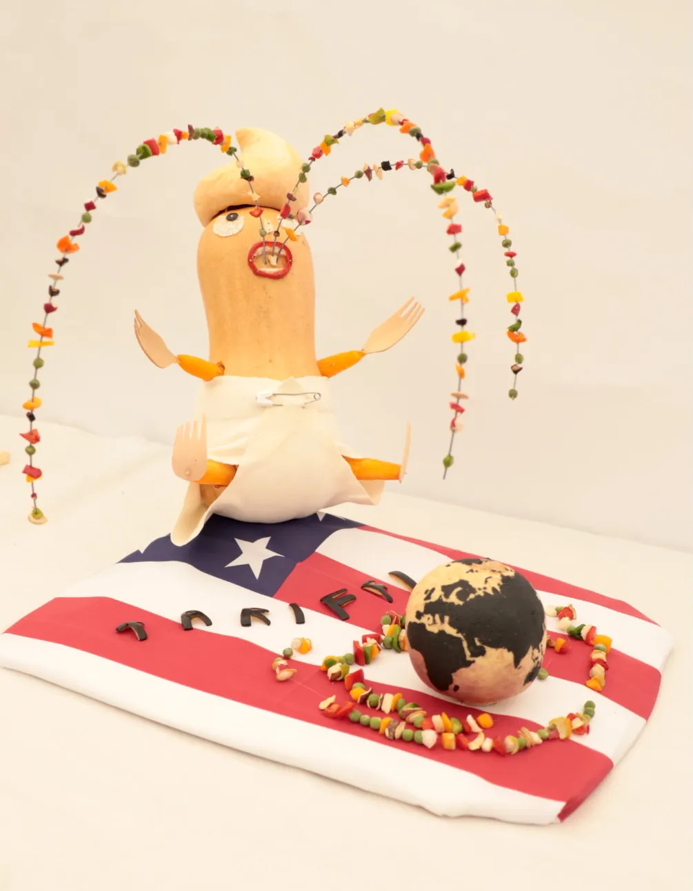 Vegetable sculpture of Donald Trump puking over the world on an American flag