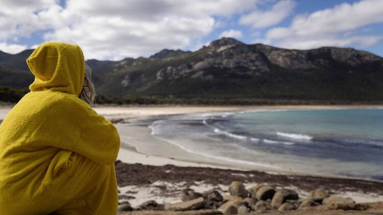 Girl sitting in yellow towel hoodie on beach