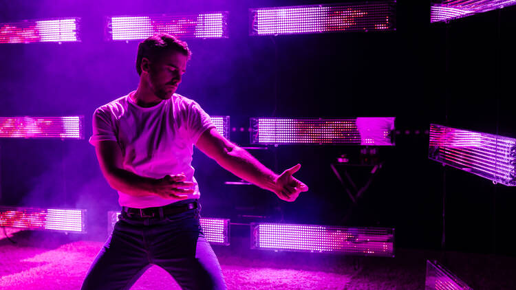 A man dancing under a purple neon light.