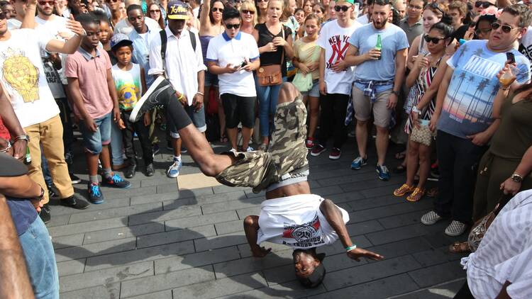 A crowd on the terrace outside the Southbank Centre watch a man spin on his head during a dance battle