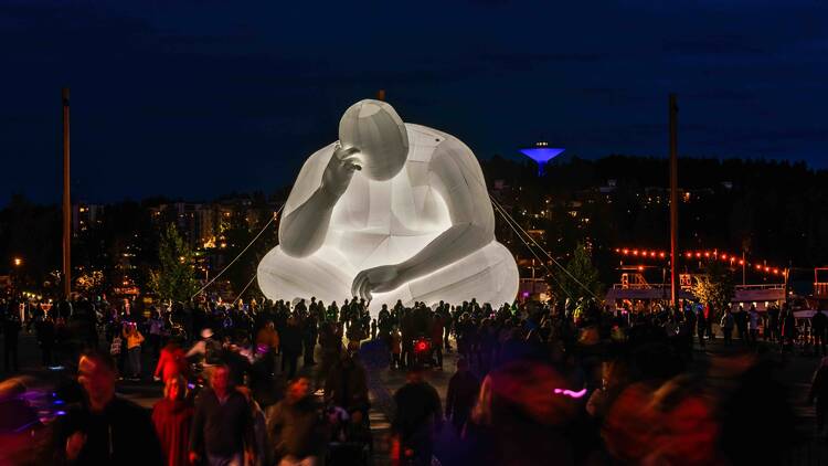 A giant inflatable sculpture of a person sitting down. 