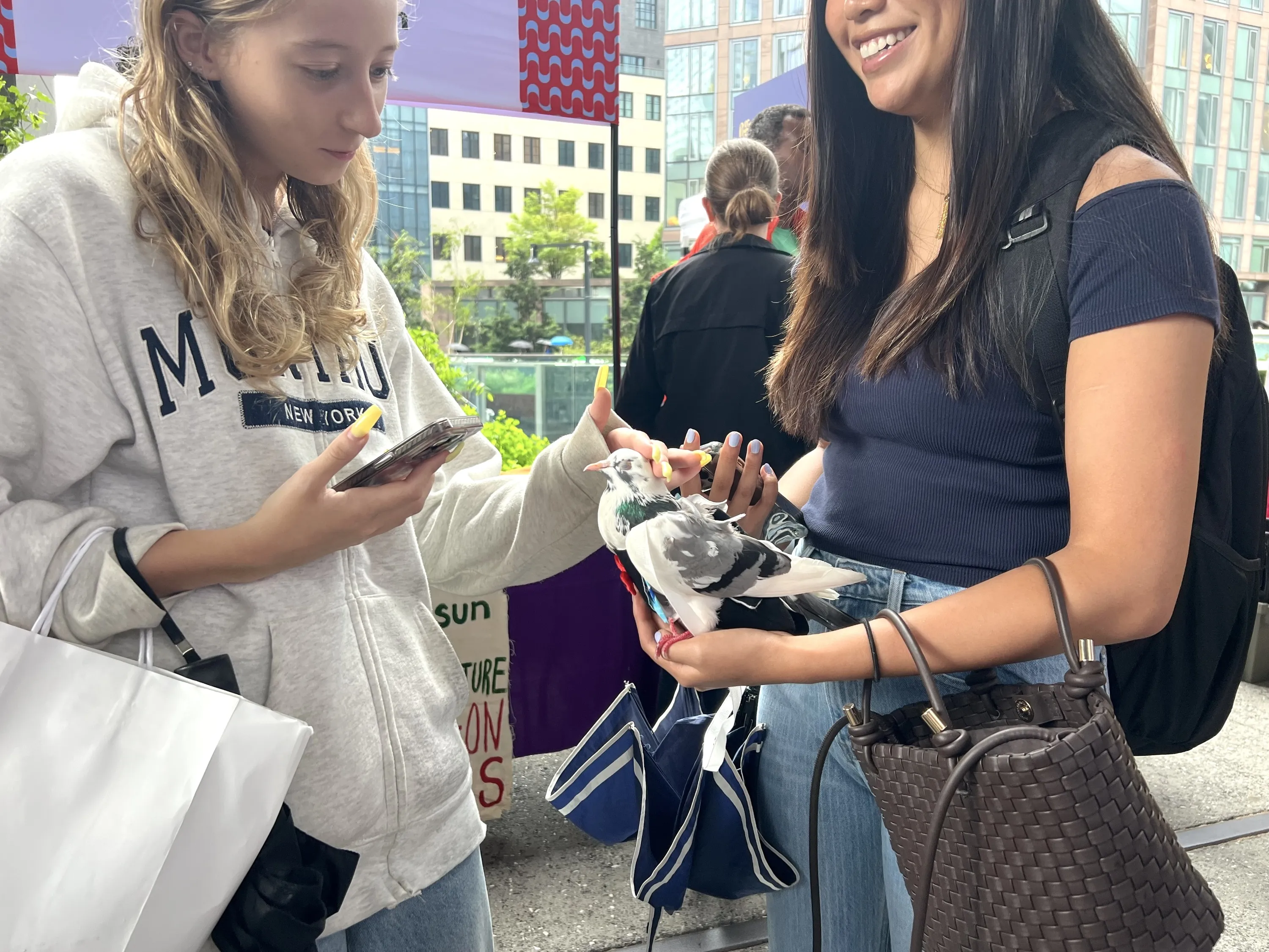 Two girls pet a pigeon.