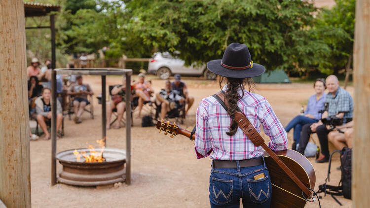 Country singer with guitar performing to audience in the outback