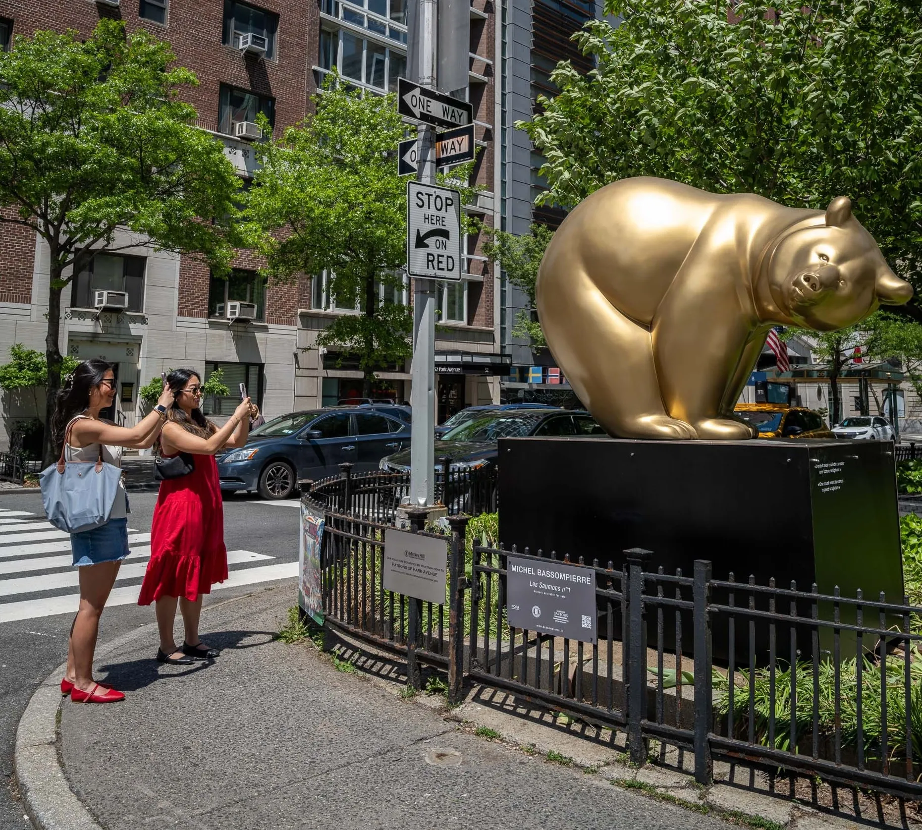 Two women stop to photograph a bear sculpture.