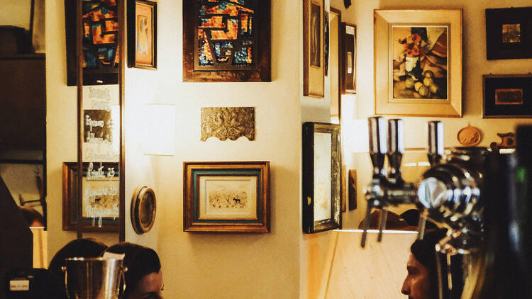 Looking over the bar at Bistrot des Serruriers, people talking with pictures hung up in the background