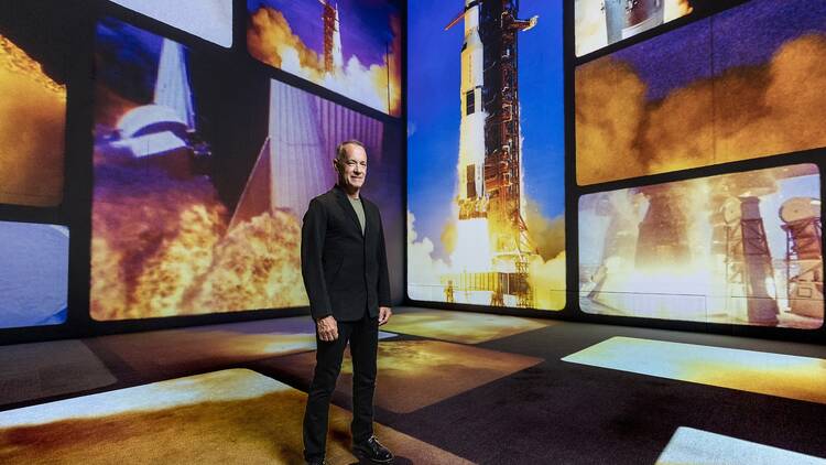 Tom Hanks in front of photos of the moon landing Tom Hanks in front of photos of the moon landing