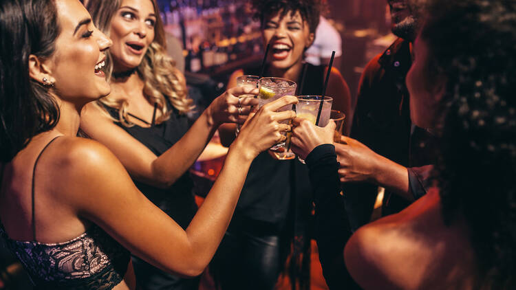 Group of friends partying in a nightclub and toasting drinks. Happy young people with cocktails at pub.