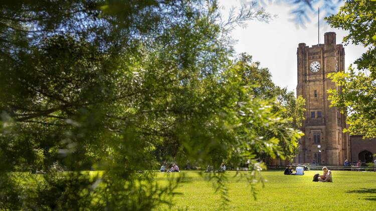 Clocktower with students sitting on grass
