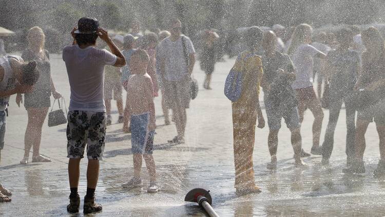 People cooling off in a street sprinkler