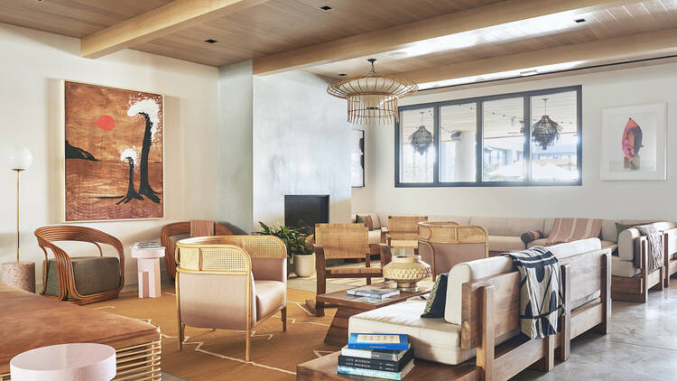 A lobby in a hotel with brown chairs and wooden beams on the ceiling.