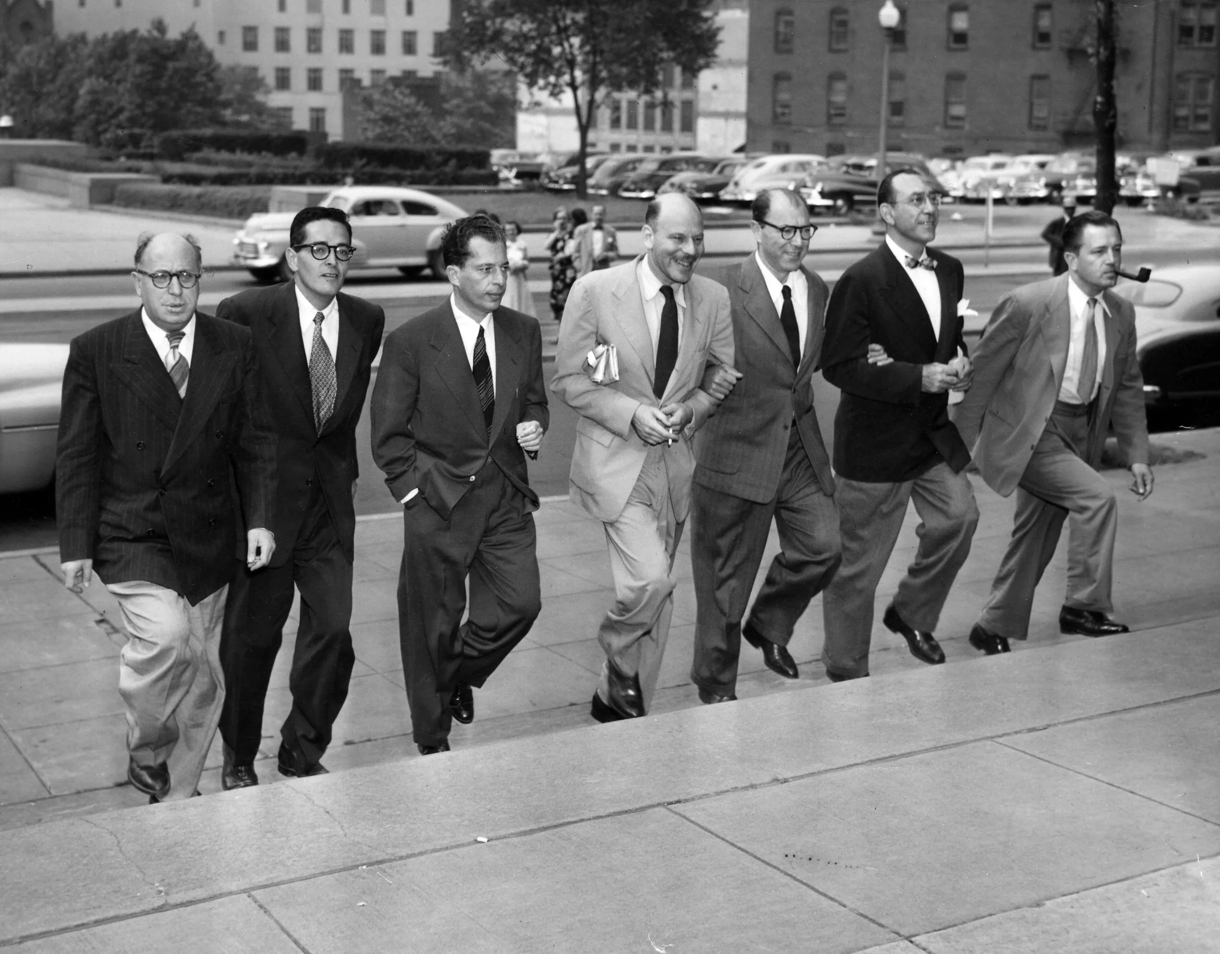 The Hollywood Ten, 1950; A group of men in suits walk up stairs together.