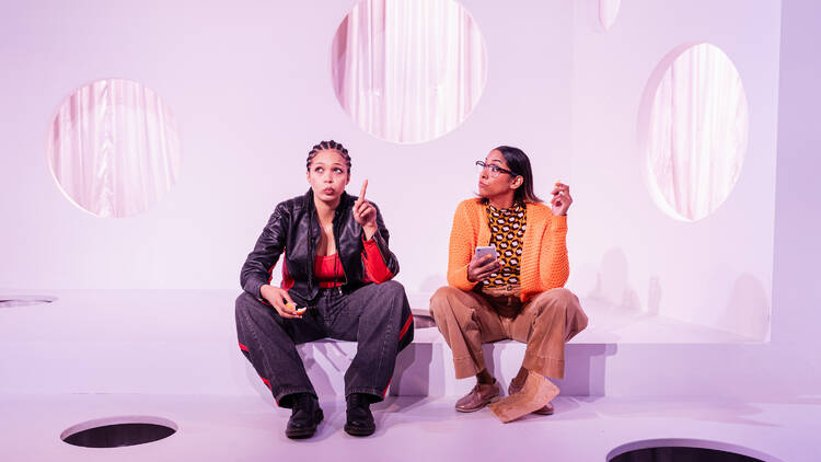 A scene from 'Super' with two actors sitting on a white set.